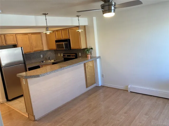 a kitchen with stainless steel appliances a stove a refrigerator a dining table and chairs with wooden floor