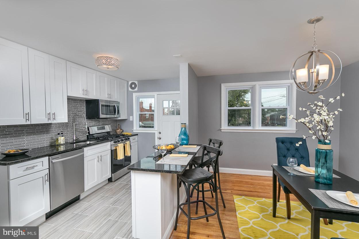 901 Stamford Road Baltimore, MD 21229 - Photo 12 of 27 a kitchen with granite countertop a stove a sink dishwasher a dining table and chairs with wooden floor