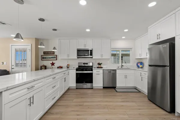 a kitchen with granite countertop a refrigerator stove top oven and sink