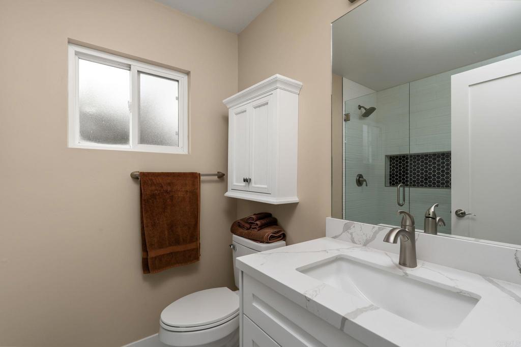 7467 Mission Gorge Road, Unit 104 Santee, CA 92071 - Photo 16 of 25 a bathroom with a granite countertop sink toilet a mirror and shower