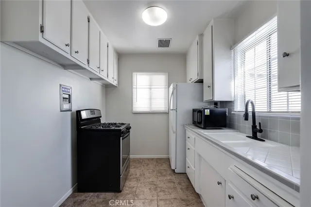 a kitchen with granite countertop a sink dishwasher stove and cabinets