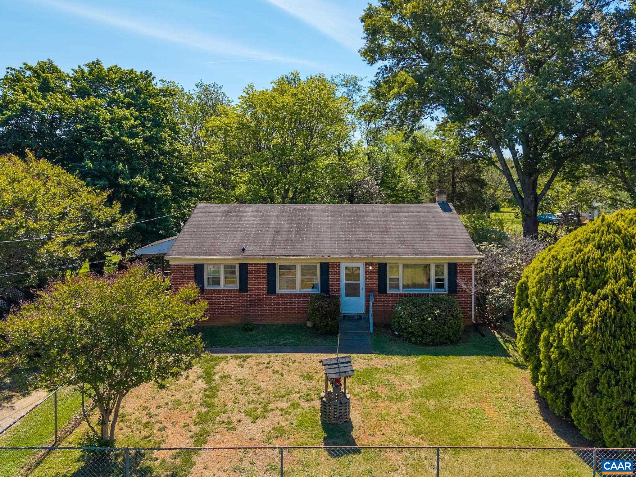 a view of a house with a yard plants and large tree