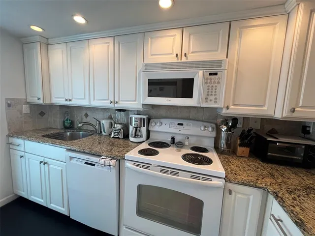 a kitchen with granite countertop white cabinets and white appliances
