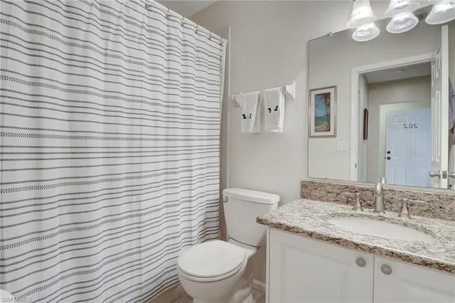a bathroom with a granite countertop toilet a sink and mirror