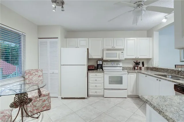 a kitchen with granite countertop white cabinets and white appliances