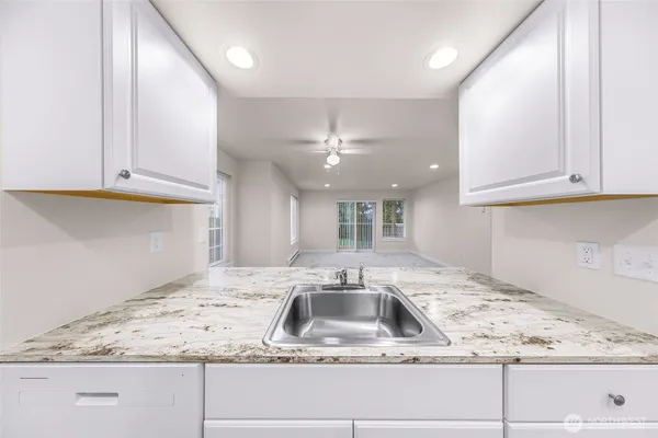 a kitchen with a sink dishwasher and white cabinets with wooden floor