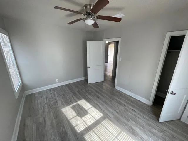 a view of empty room with wooden floor and fan