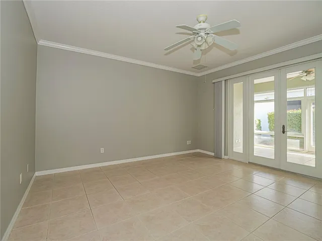 an empty room with chandelier fan and windows