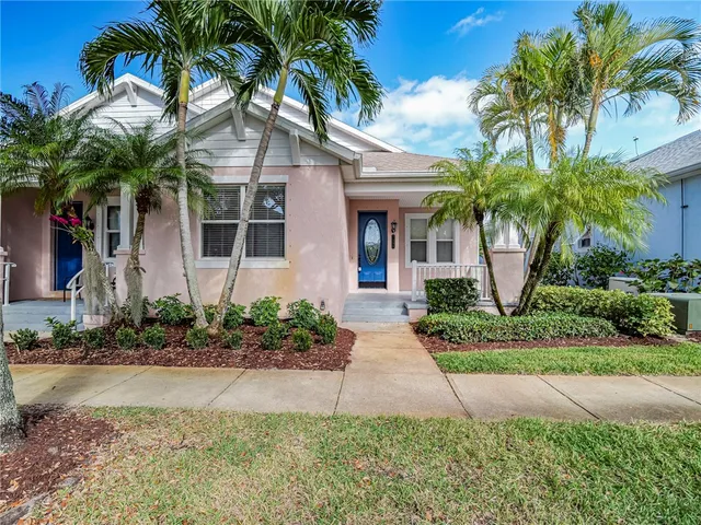 a front view of a house with a yard and palm trees