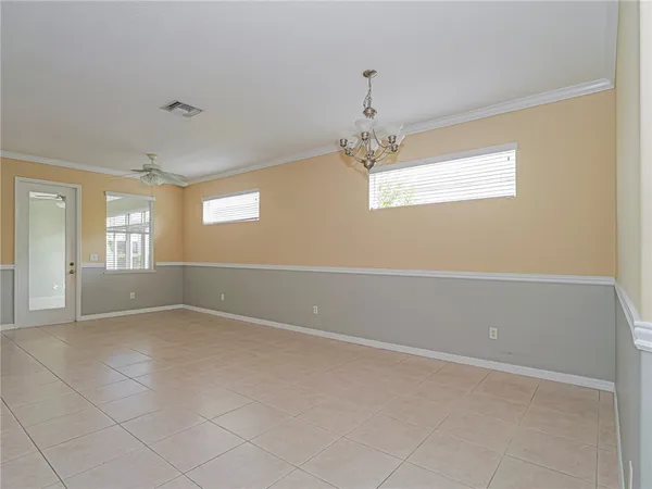 an empty room with windows and chandelier fan