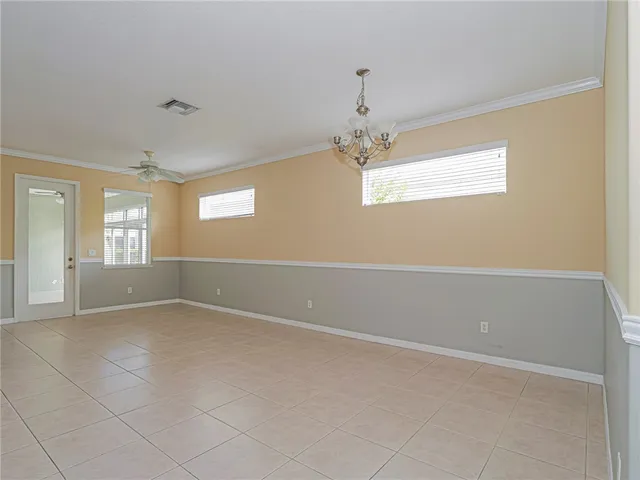 an empty room with windows and chandelier fan