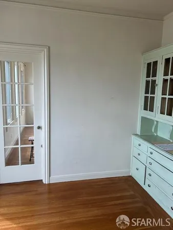 an empty room with wooden floor and cabinet