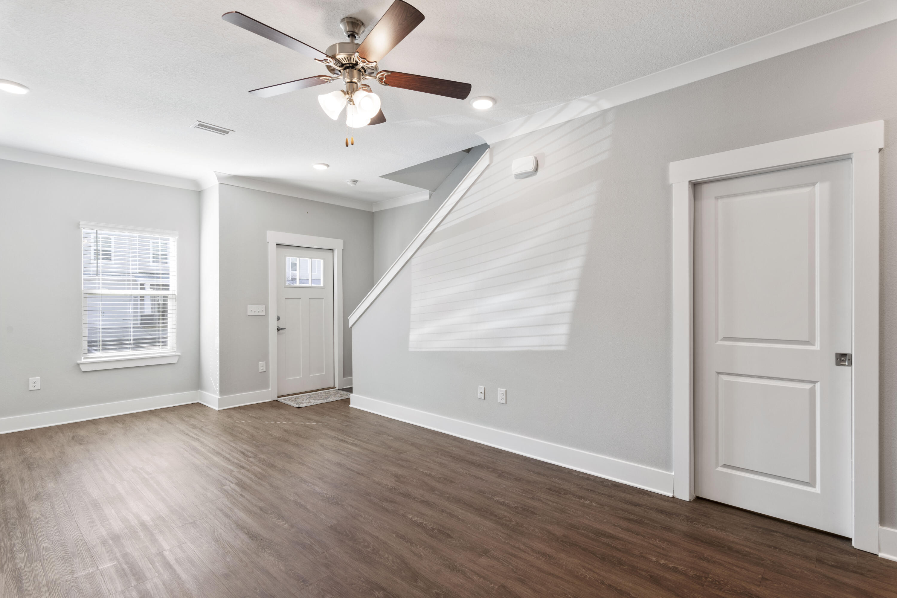 296 North Sand Palm Road Freeport, FL 32439 - Photo 6 of 30 an empty room with wooden floor chandelier fan and windows