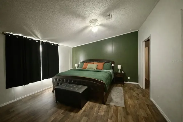 a bedroom with a bed and a flat tv screen on dresser
