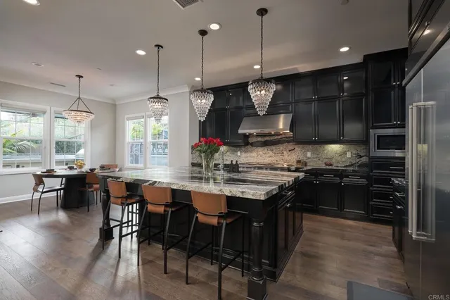 a kitchen with stainless steel appliances granite countertop wooden floors stove and white cabinets