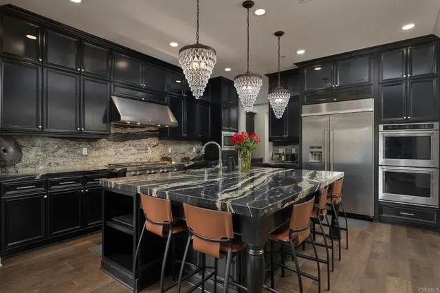 a kitchen with stainless steel appliances granite countertop a stove a refrigerator a kitchen island a sink and a refrigerator