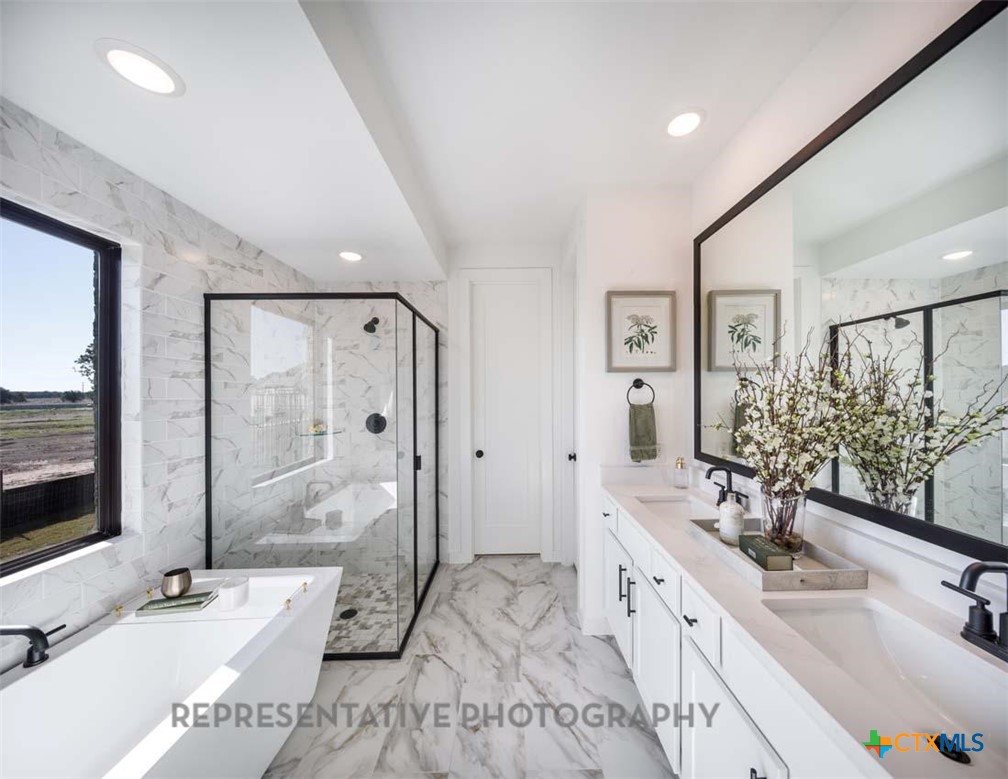 133 Three Oaks Lane Georgetown, TX 78628 - Photo 18 of 40 a spacious bathroom with a double vanity sink a large mirror a shower and a bathtub