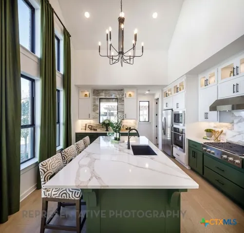 a large kitchen with stainless steel appliances granite countertop a dining table and chairs