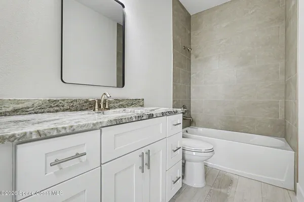a bathroom with a granite countertop sink a toilet and a bathtub