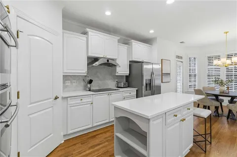 a kitchen that has a lot of white cabinets and stainless steel appliances