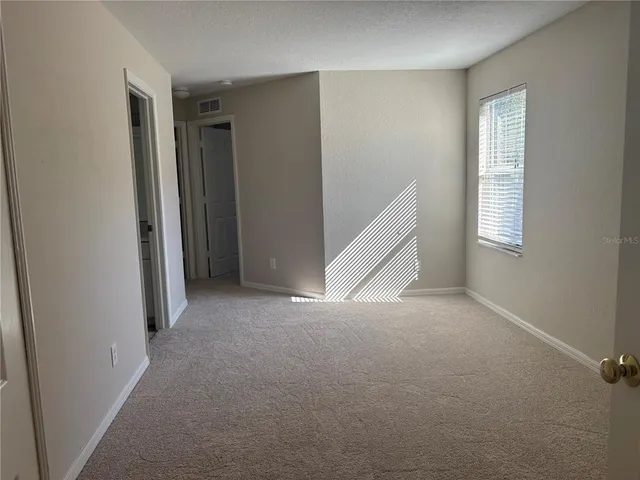 a view of an empty room with closet and wooden door
