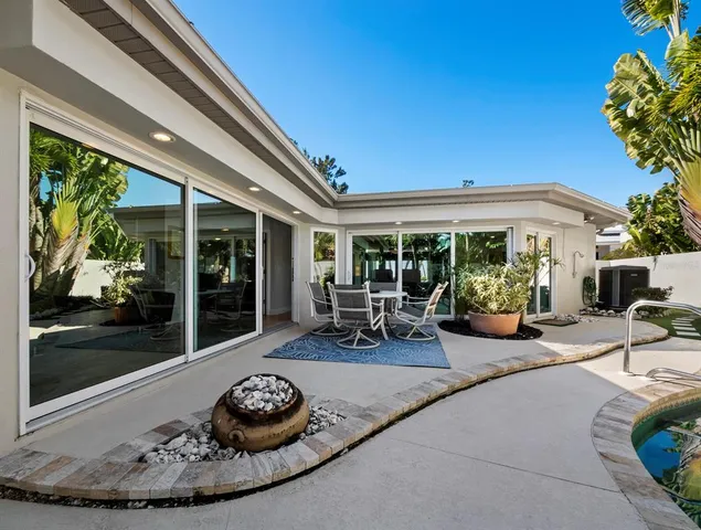 a view of a patio with table and chairs potted plants and floor to ceiling window