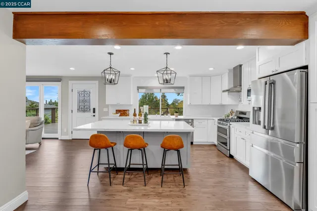 a kitchen with stainless steel appliances granite countertop a table chairs sink and cabinets