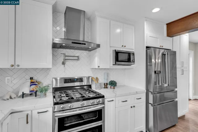 a kitchen with stainless steel appliances granite countertop a stove a refrigerator and a white cabinets