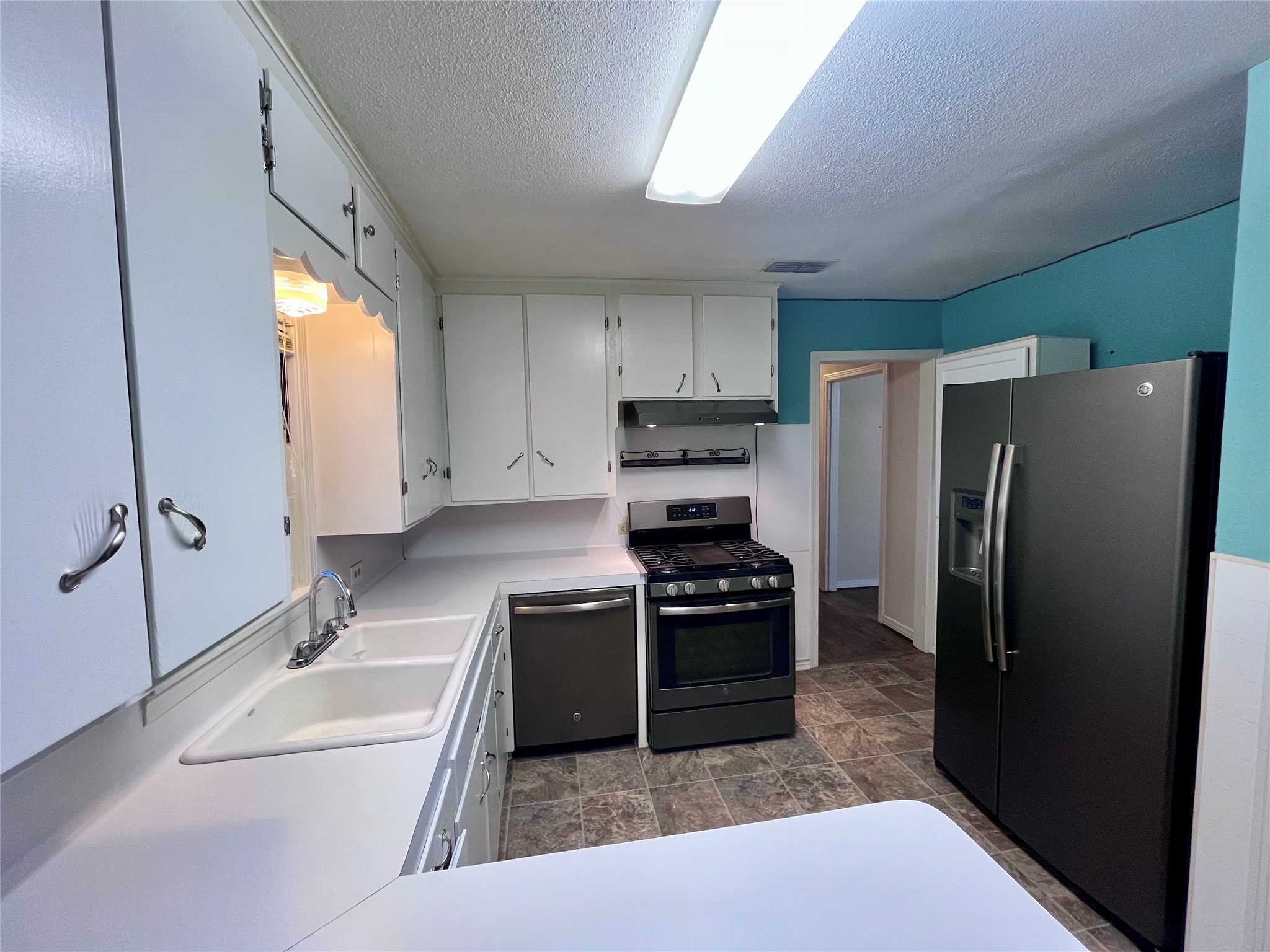 1004 North Center Street Weimar, TX 78962 - Photo 5 of 15 a kitchen with stainless steel appliances granite countertop a refrigerator a stove a sink and a microwave