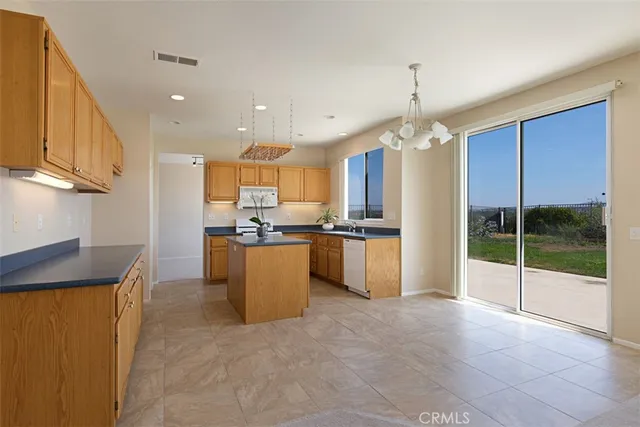 a view of a kitchen with kitchen island granite countertop a refrigerator a sink a dining table and chairs