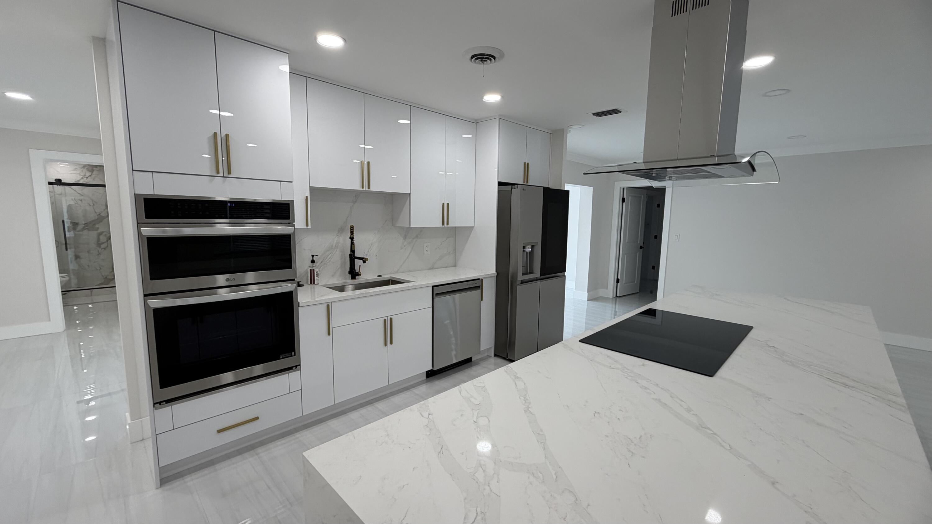 2521 Northeast 45th Street Lighthouse Point, FL 33064 - Photo 7 of 25 a kitchen with stainless steel appliances kitchen island granite countertop a refrigerator and a stove top oven