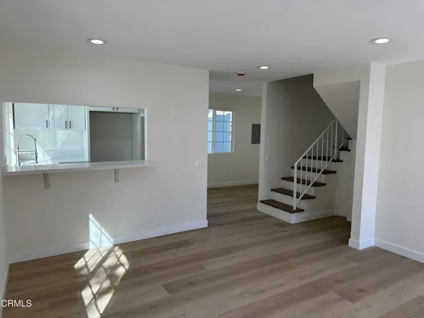a view of an empty room with wooden floor and stairs