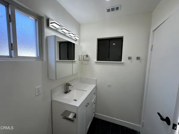 a bathroom with a sink a light fixture and a mirror