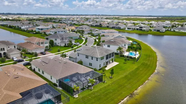a view of a brick house with a yard large plants and large tree