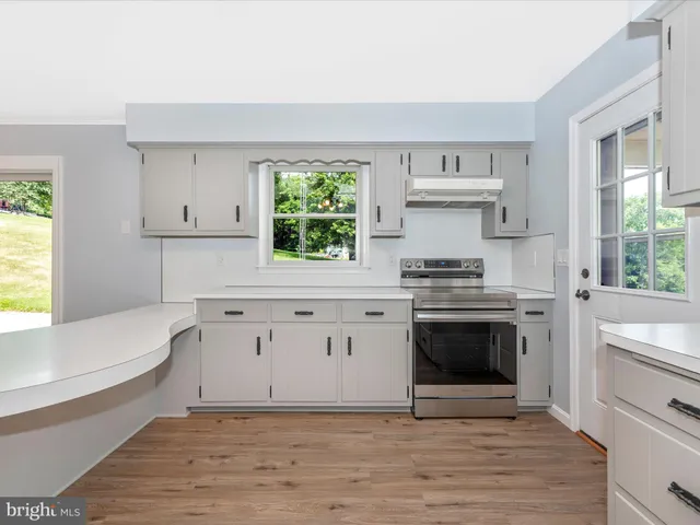 a kitchen with stainless steel appliances granite countertop a refrigerator a sink and white cabinets