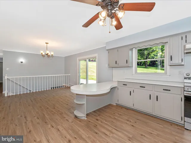 a kitchen with granite countertop white cabinets and white appliances with wooden floor