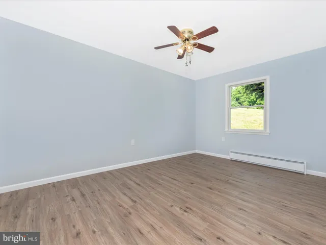an empty room with wooden floor chandelier fan and closet area