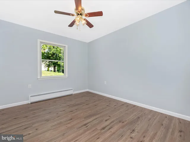 a view of an empty room with wooden floor and window