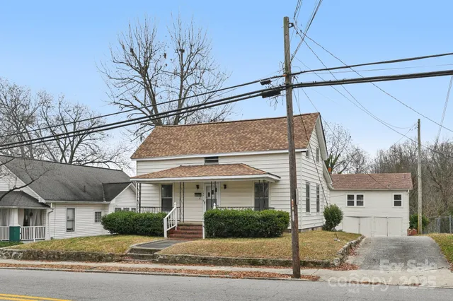 a view of a white house next to a road and yard