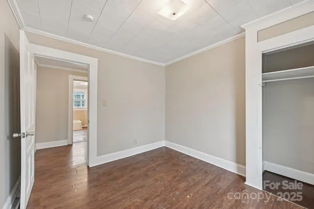 an empty room with wooden floor closet and windows