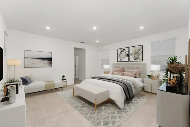 a spacious bedroom with a bed a couch and a potted plant