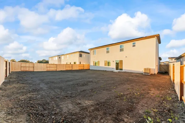 a view of a white house with a small yard and large tree
