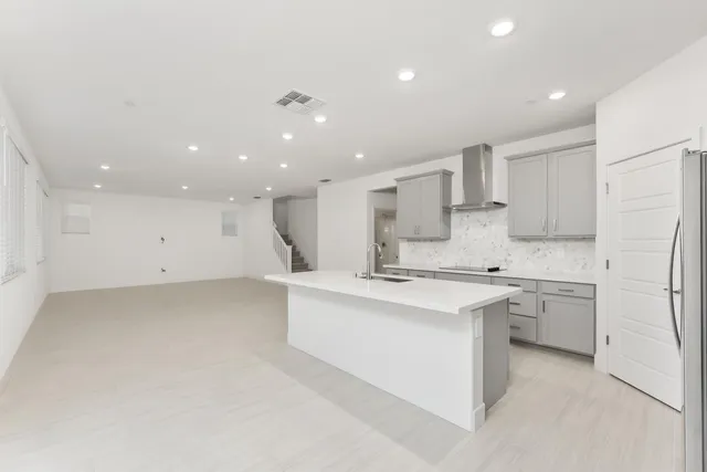 a large white kitchen with a stove a sink a refrigerator and white cabinets