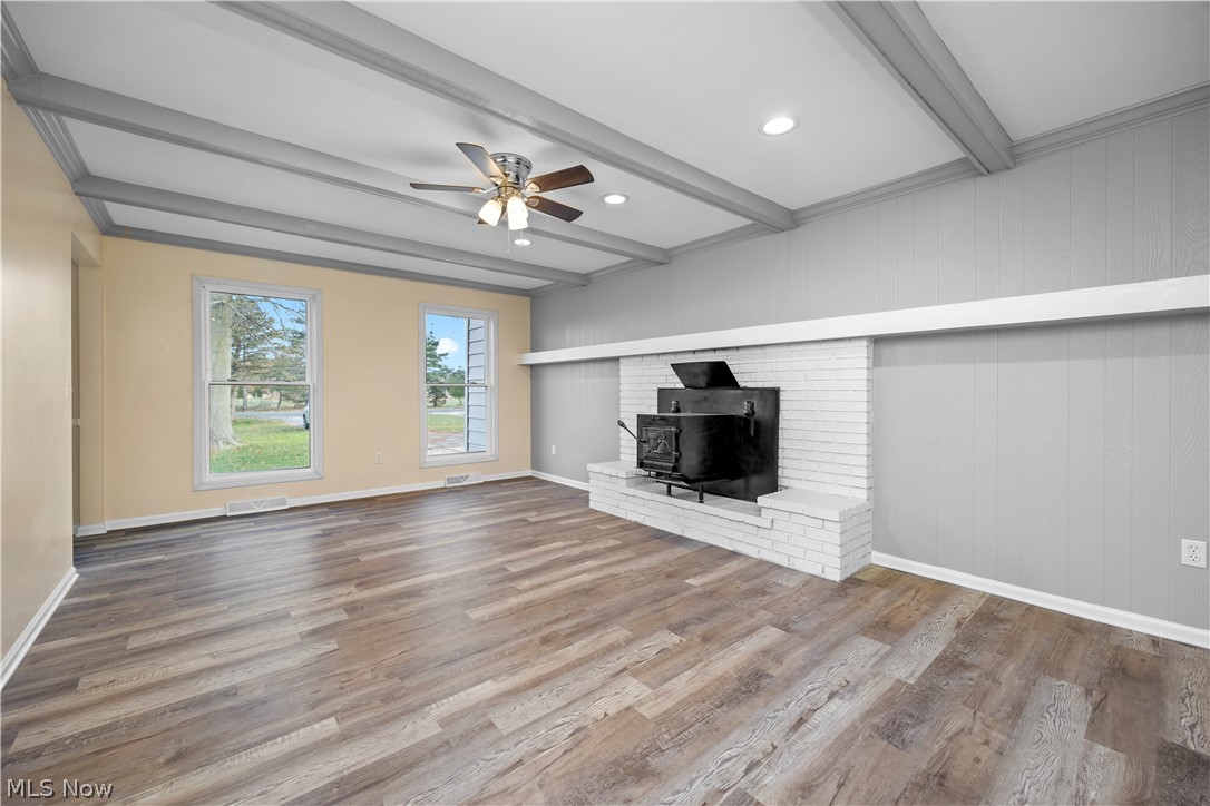 34725 Capel Road Columbia Station, OH 44028 - Photo 12 of 47 Spacious room featuring wood-finish flooring and a white brick fireplace with a black wood-burning insert