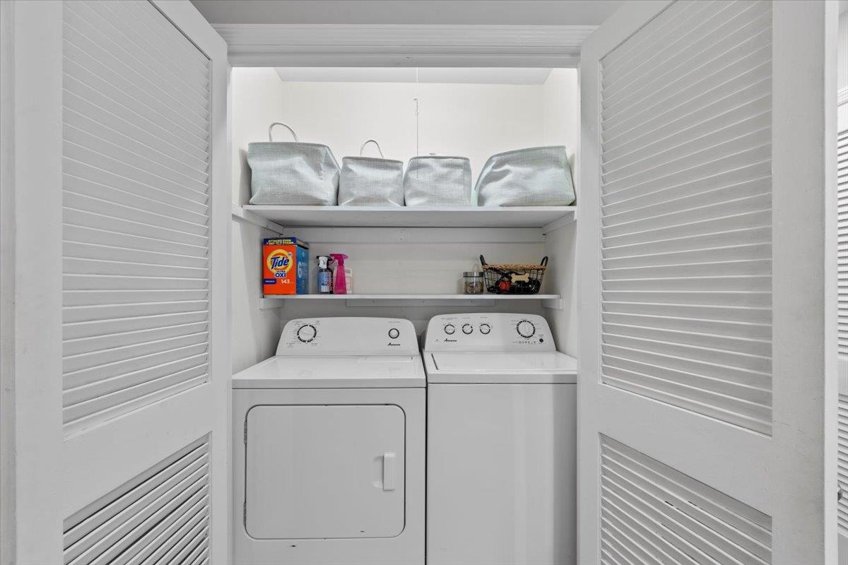 4491 Garnett Road Memphis, TN 38117 - Photo 22 of 32 Dedicated laundry area featuring a white top-load washer and dryer set, white louvered bifold doors, and integrated shelving