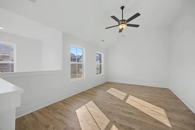 a view of empty room with wooden floor and ceiling fan