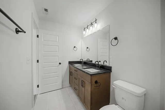 a bathroom with a granite countertop sink a toilet and a mirror