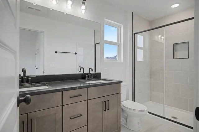a bathroom with a granite countertop sink a toilet and shower