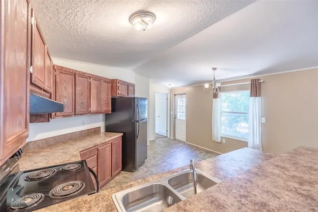 a kitchen with stainless steel appliances granite countertop a refrigerator and a stove top oven