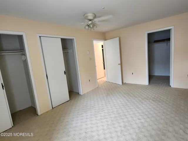 an empty room with closet and a ceiling fan